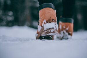 Close-up of person wearing boots walking in snow, capturing the essence of winter outdoors.