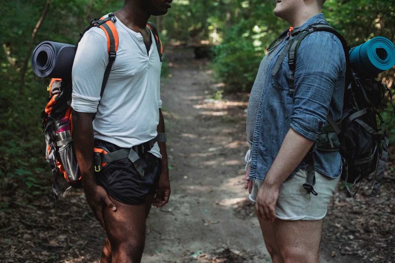 Two men hiking and talking on a lush forest trail, conveying adventure and tranquility.